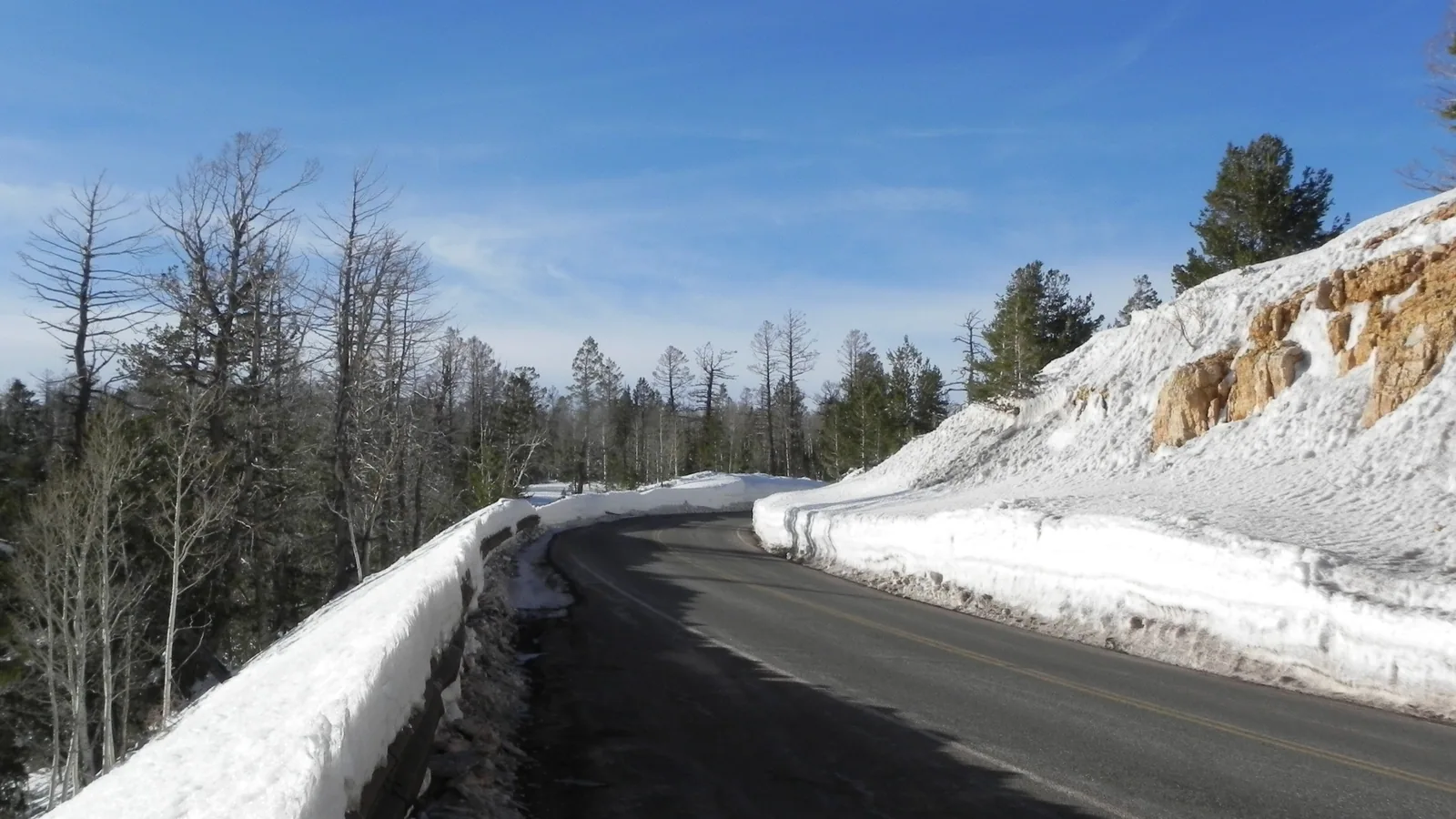 Plowed two lane Highway 14 between tall snowbanks in pine and aspen forest near Navajo Lake, Utah, photographed in January