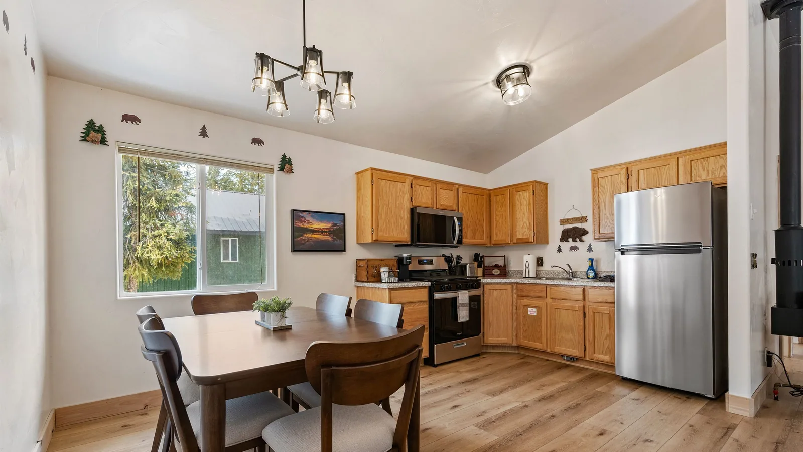 Kitchen and dining area of a Duck Creek Village Inn cabin with a full size refrigerator, gas range and a table under the window