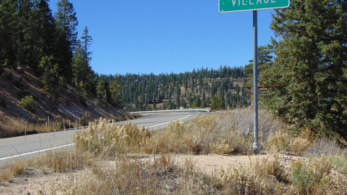 Highway 14 at the Duck Creek Village boundary, pine timber on both sides of the road
