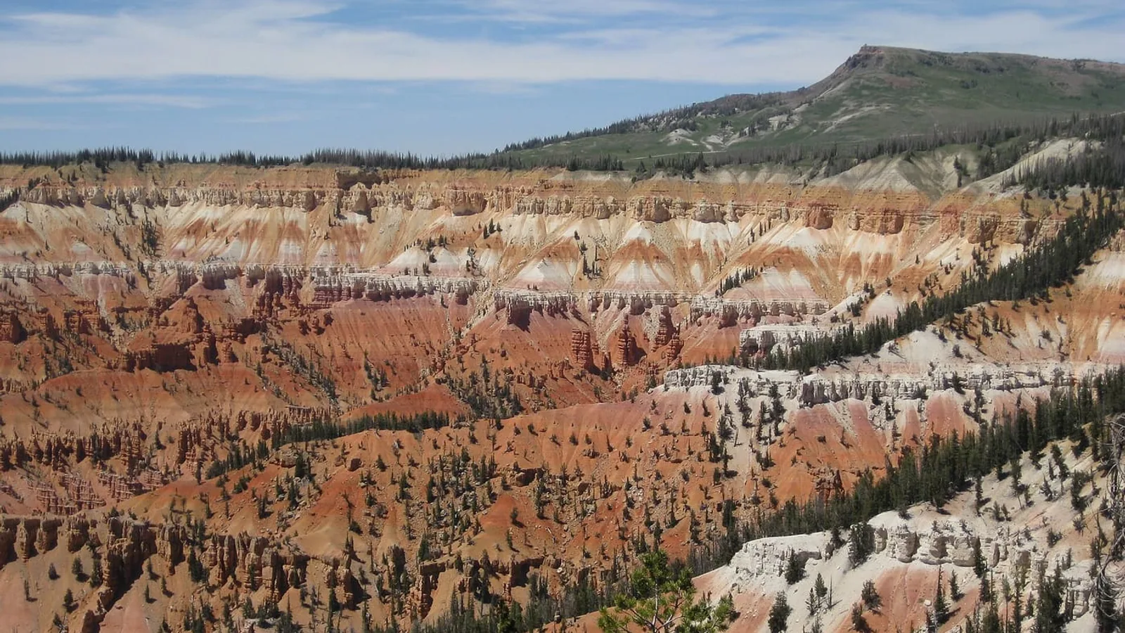 Das Amphitheater der Cedar Breaks vom Rand aus gesehen, mit dem Brian Head Peak am Horizont über dem roten Fels